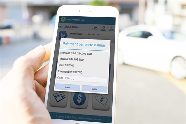 Un recouvreur tient son smartphone dans la rue : Smart PAYMENT affiche la fenêtre de paiement par carte e-dinar, le détail des montants et le champ du code PIN.