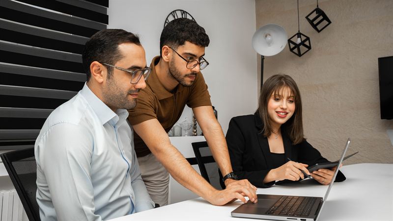 Trois collaborateurs de SYMATIQUE réunis autour d'un ordinateur portable, en salle de réunion au siège de Tunis.